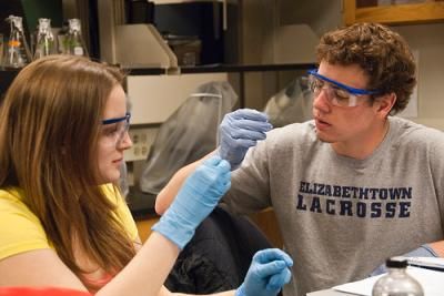 two students looking at test tubes with goggles on 