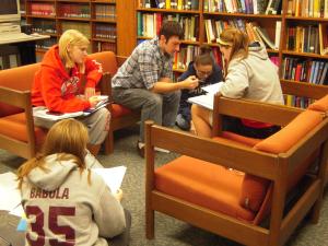 students sitting on couches and floor working in chemistry library surrounded by books