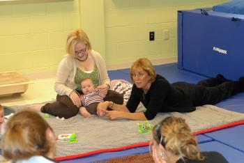 kid zone professor and students with babies on mat