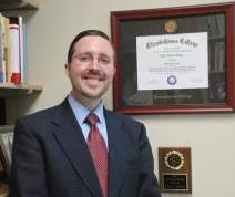 dr. kyle kopko in front of his framed diploma