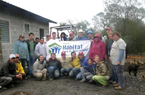 students and faculty group picture in front of habitat for humanity sign on trip to hondorous with 