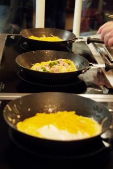 omelet station close up shot of three pans of omelets cooking