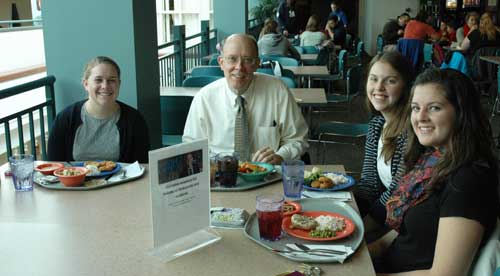 president strikwerda with three female students in marketplace