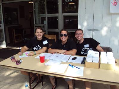 three resident assistants two female one male seat at registration table on movie-in day
