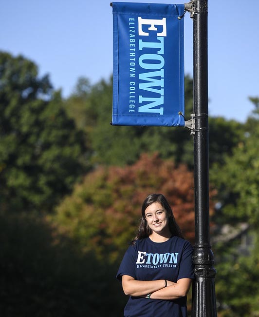 Student standing by flag