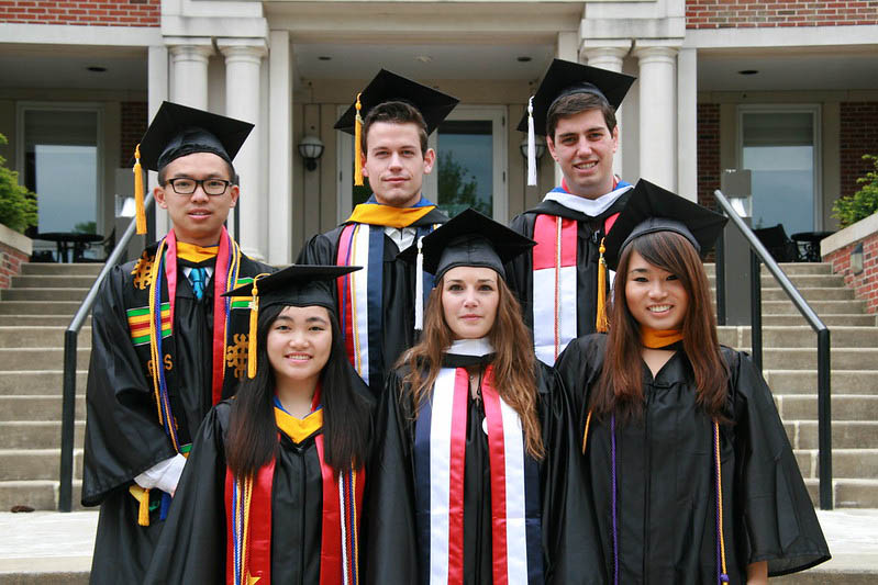 students in graduation caps on steps of library