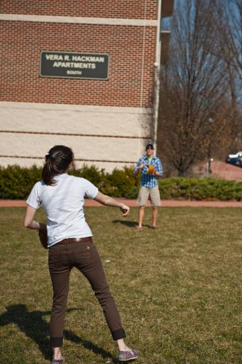 male and female students playing catch in front of hackman apartments male and female students playing catch in front of hackman apartments